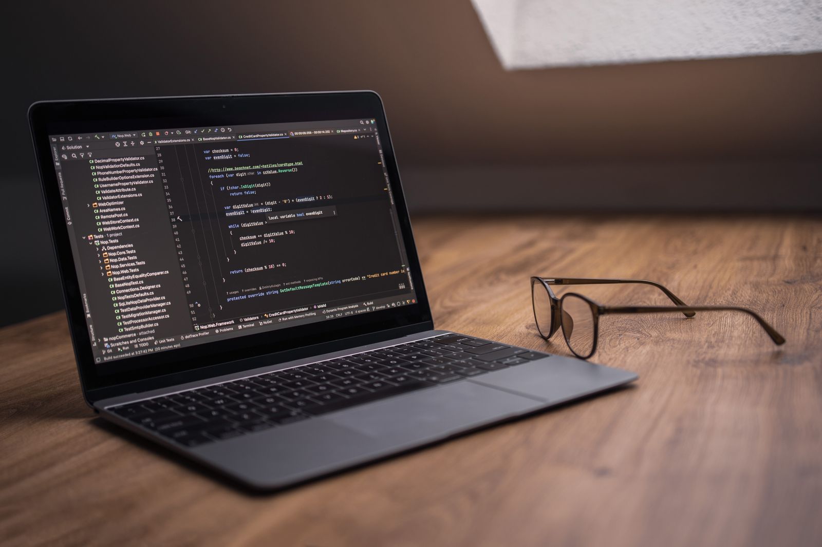 Computer portatile con editor di codice aperto, immagine illustrativa dei programmi installati e delle cartelle software in Windows.
