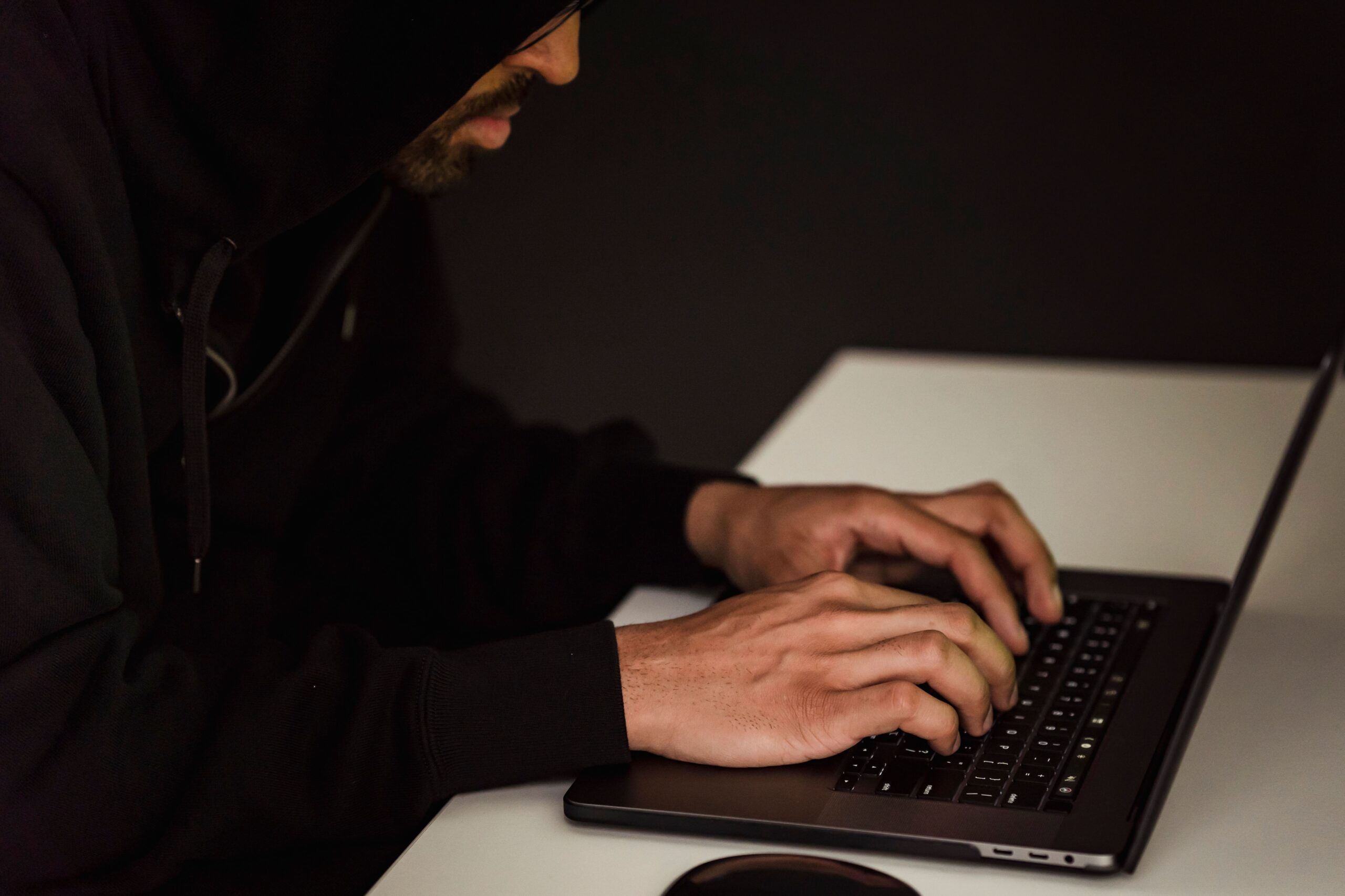Persona al computer in un ambiente poco illuminato, immagine illustrativa sui rischi informatici e sul ransomware.